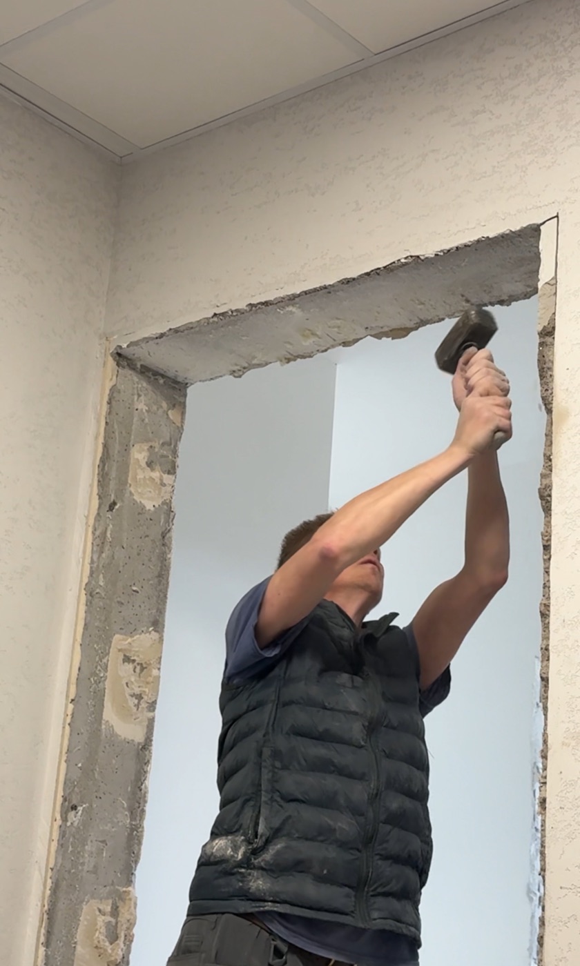 Монтажник выравнивает верхнюю часть дверного проёма